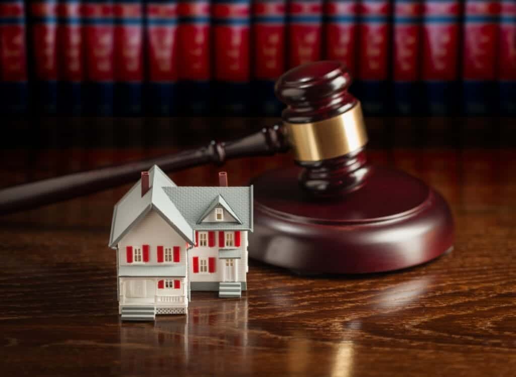 Gavel and Small Model House on Wooden Table.