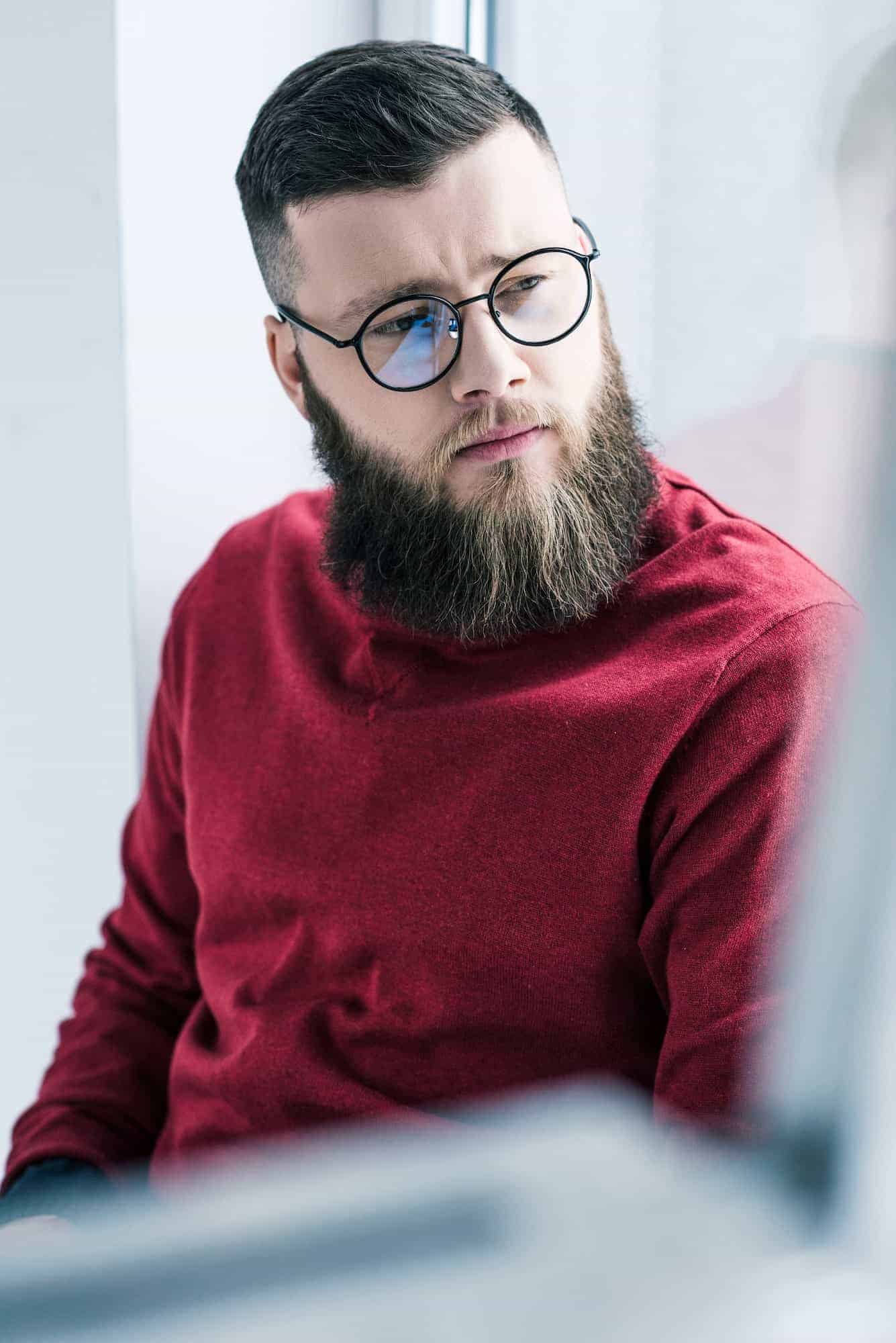 portrait of handsome pensive businessman in eyeglasses looking away