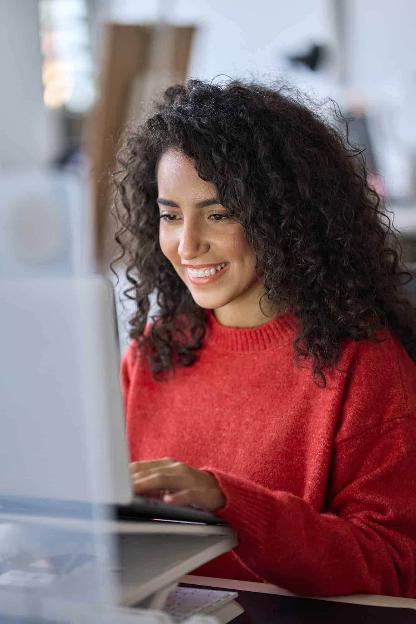 Young happy latin woman student elearning using laptop. Vertical shot